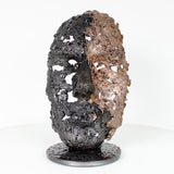 Cette sculpture représente un visage humain, créé avec une technique de dentelle de métal unique.