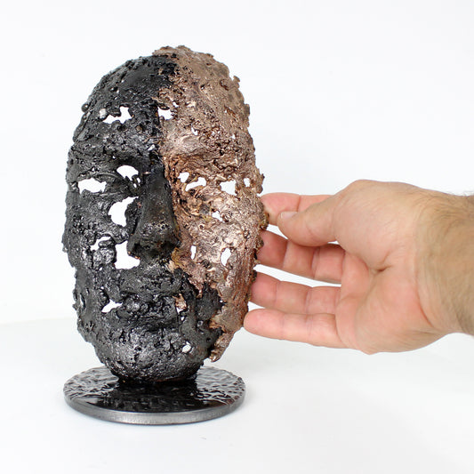 Cette sculpture représente un visage humain, créé avec une technique de dentelle de métal unique.