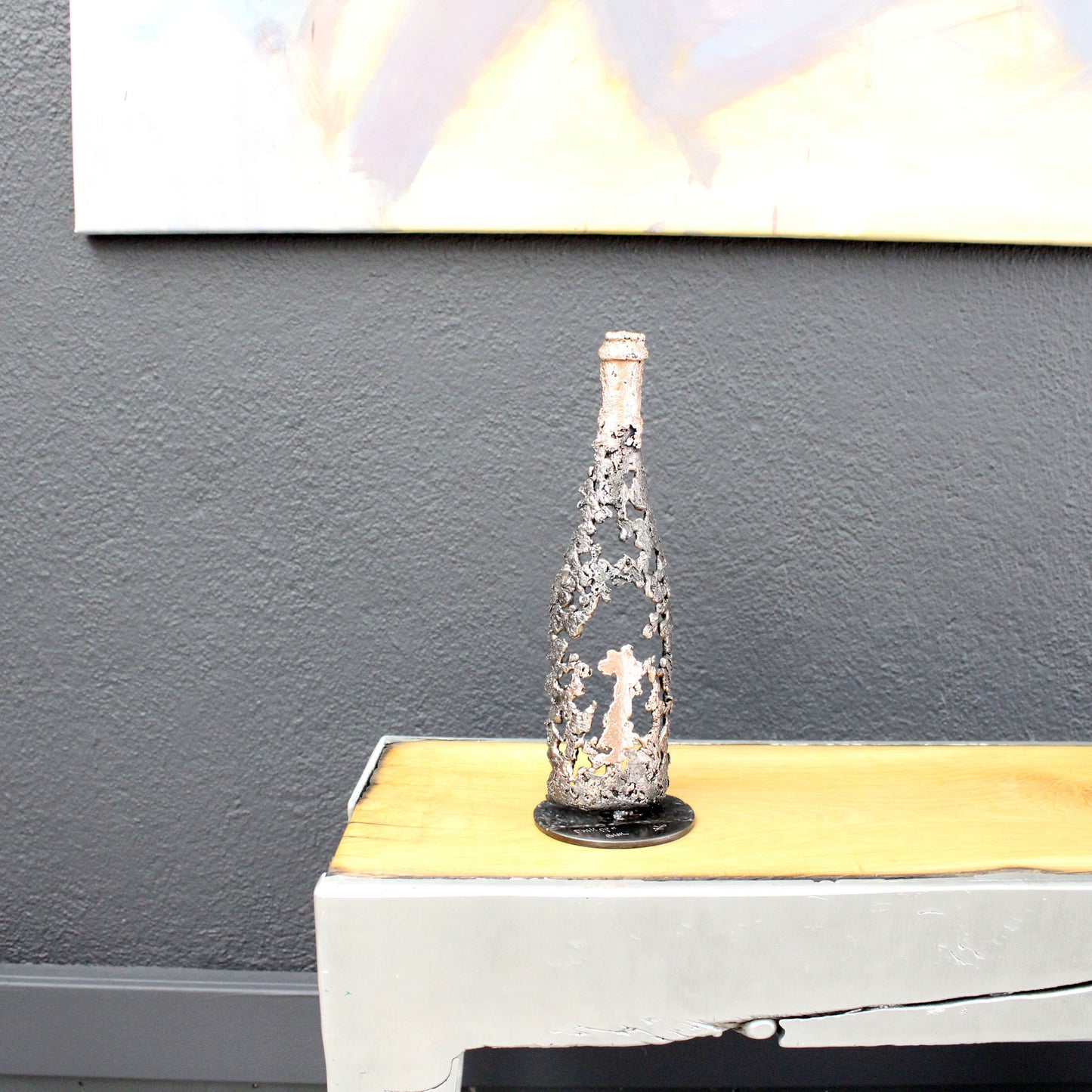 Sculpture de Philippe Buil représentant une bouteille de champagne en dentelle de métal : acier et bronze