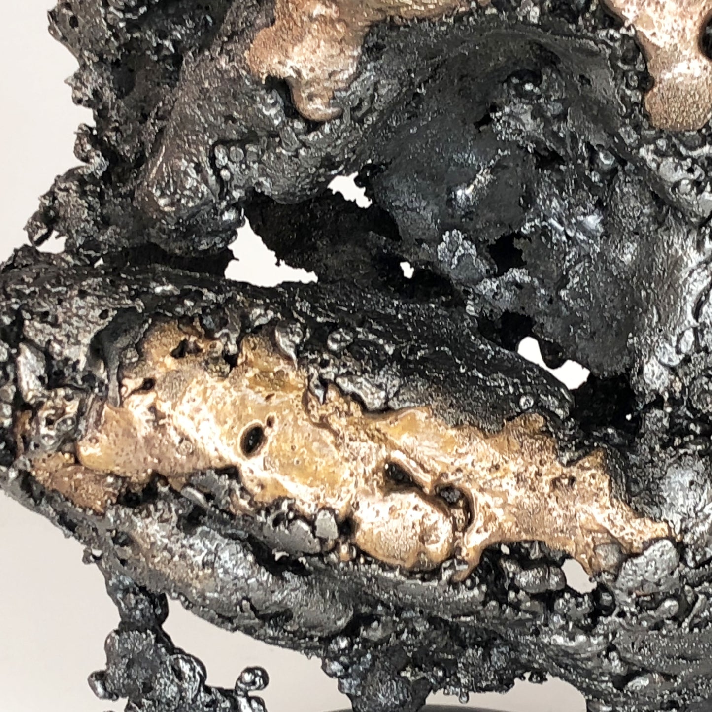 Sculpture de Philippe Buil représentant un corps d'homme accroupi intégré à une forme évoquant une montagne. Sculpture en dentelle de métal : acier et bronze.