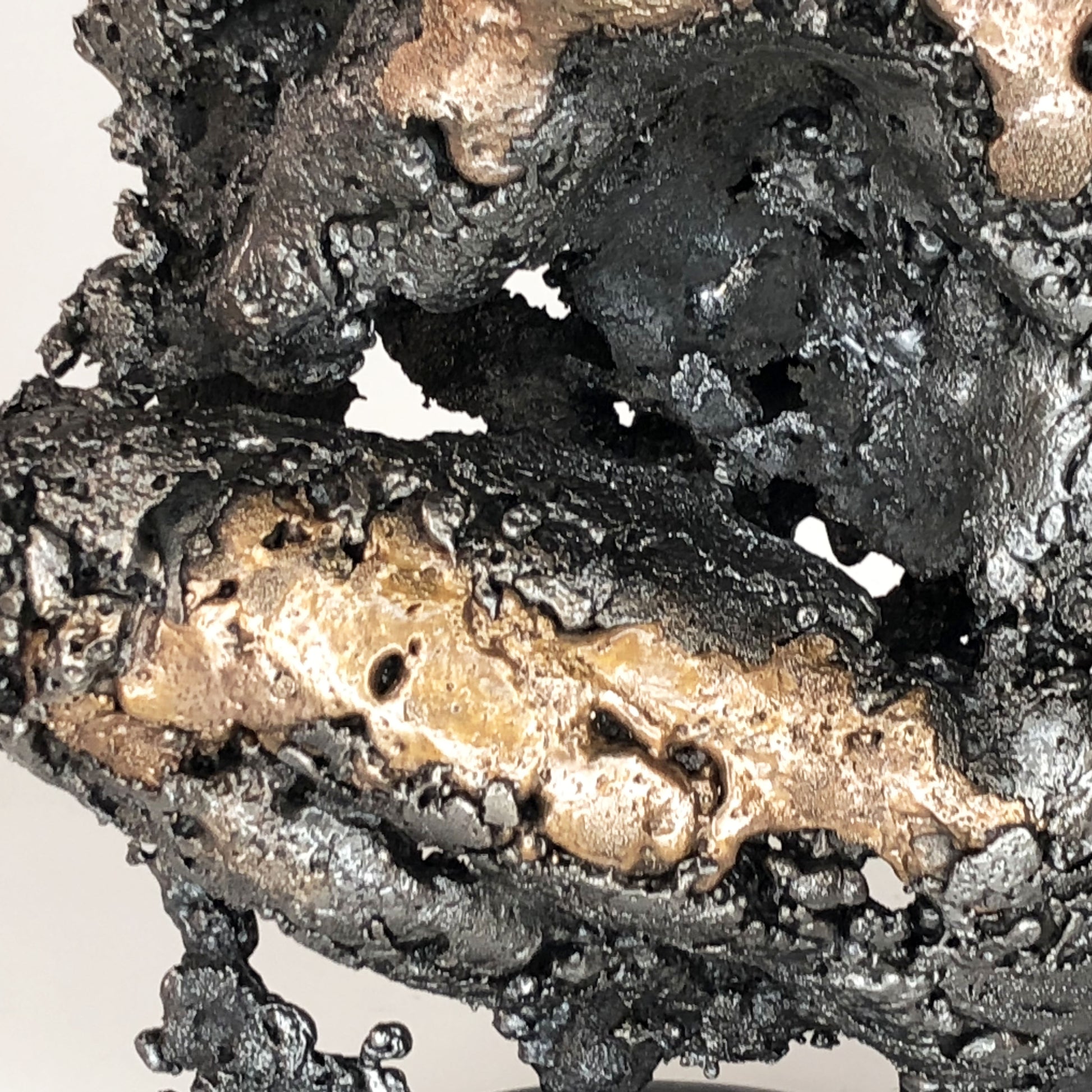 Sculpture de Philippe Buil représentant un corps d'homme accroupi intégré à une forme évoquant une montagne. Sculpture en dentelle de métal : acier et bronze.