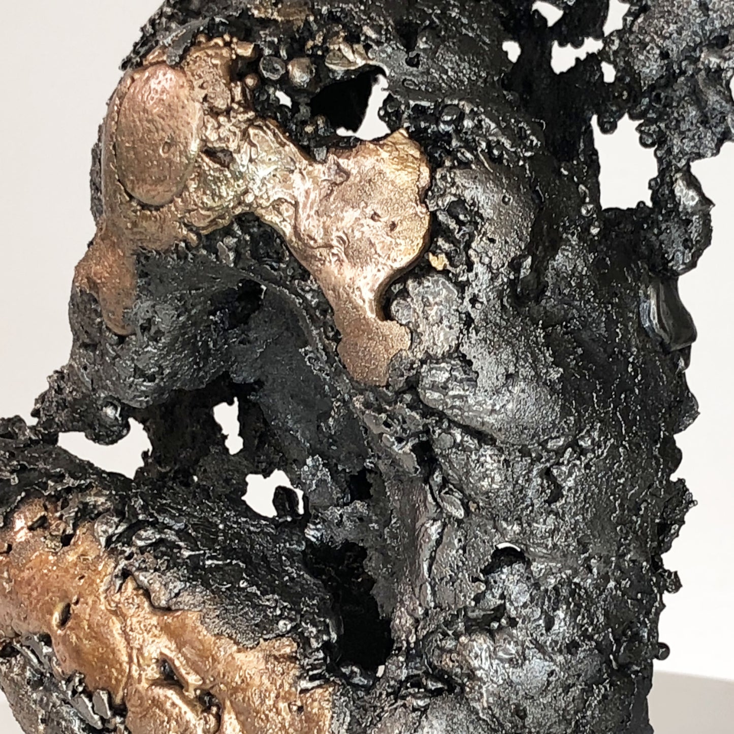 Sculpture de Philippe Buil représentant un corps d'homme accroupi intégré à une forme évoquant une montagne. Sculpture en dentelle de métal : acier et bronze.