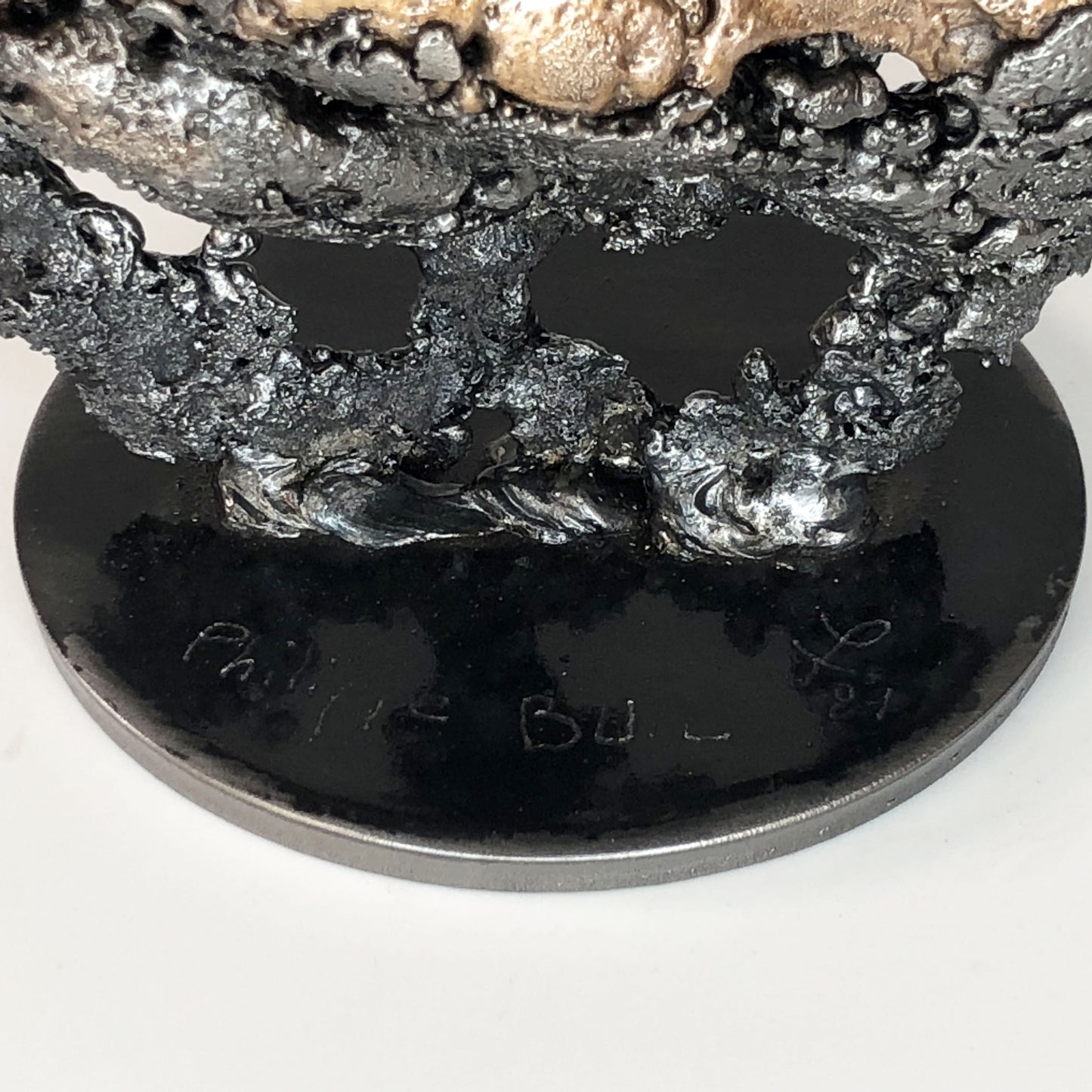 Sculpture de Philippe Buil représentant un corps d'homme accroupi intégré à une forme évoquant une montagne. Sculpture en dentelle de métal : acier et bronze.