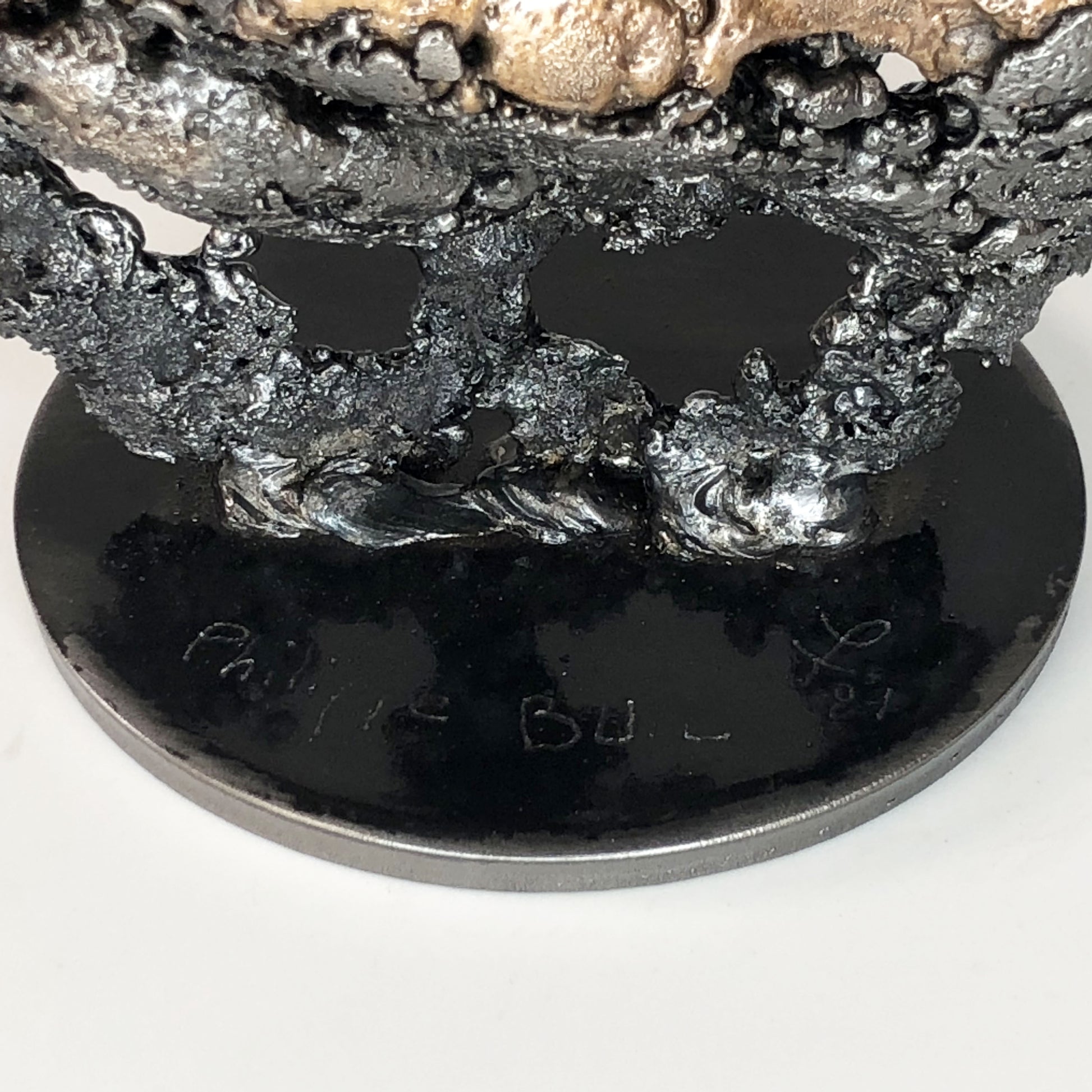 Sculpture de Philippe Buil représentant un corps d'homme accroupi intégré à une forme évoquant une montagne. Sculpture en dentelle de métal : acier et bronze.