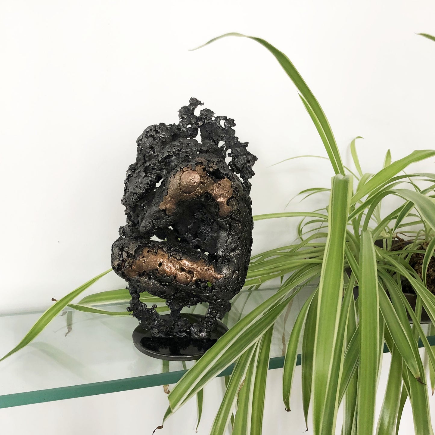 Sculpture de Philippe Buil représentant un corps d'homme accroupi intégré à une forme évoquant une montagne. Sculpture en dentelle de métal : acier et bronze.