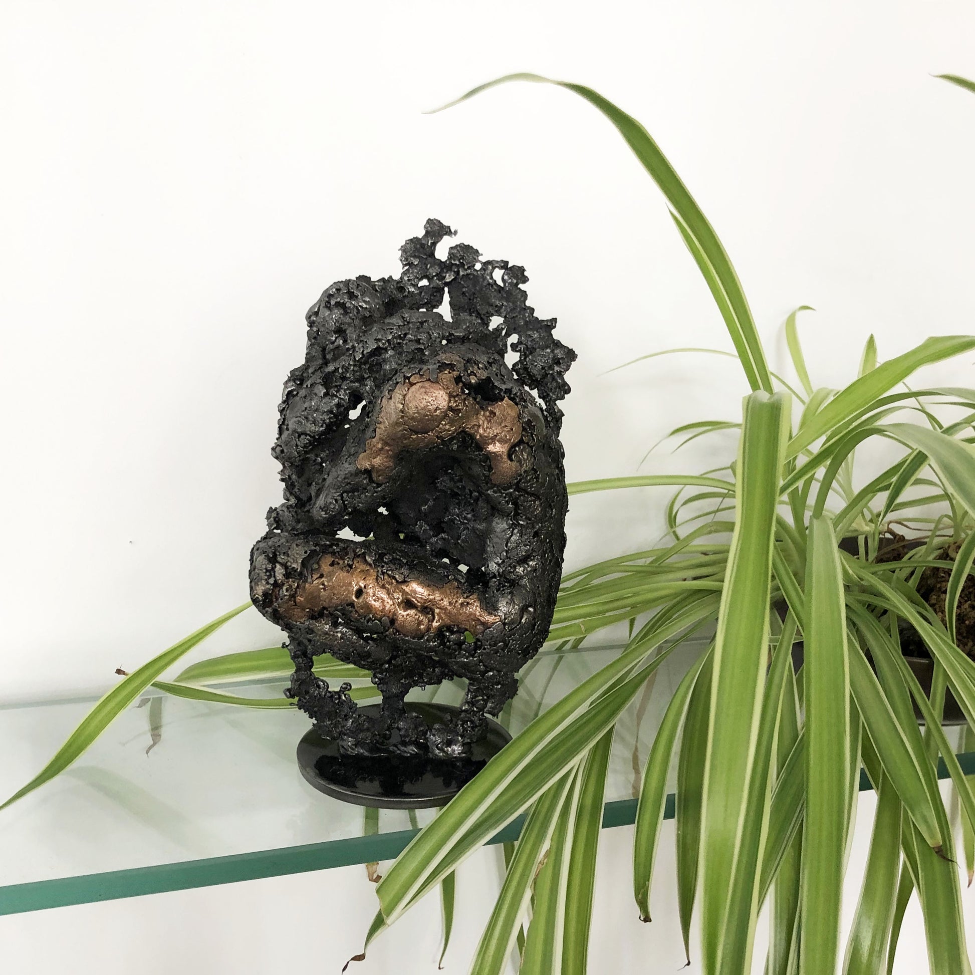 Sculpture de Philippe Buil représentant un corps d'homme accroupi intégré à une forme évoquant une montagne. Sculpture en dentelle de métal : acier et bronze.