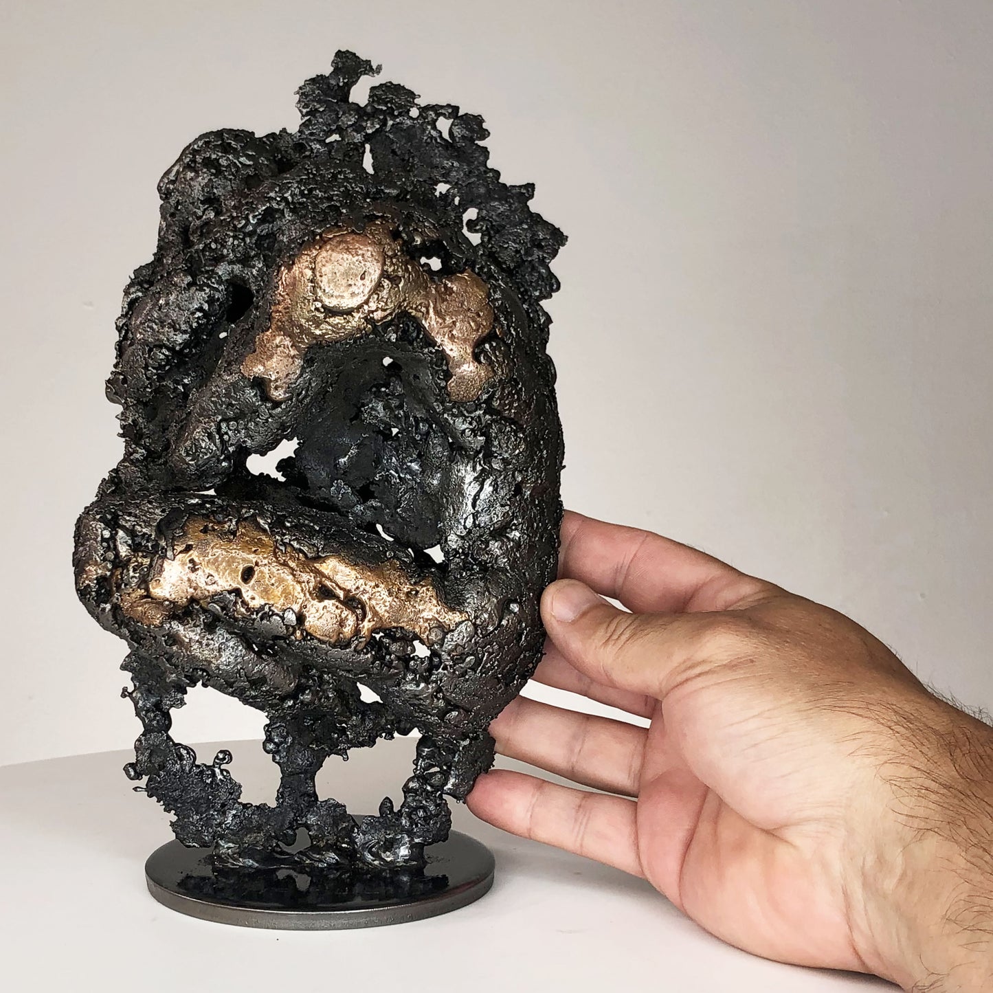 Sculpture de Philippe Buil représentant un corps d'homme accroupi intégré à une forme évoquant une montagne. Sculpture en dentelle de métal : acier et bronze.