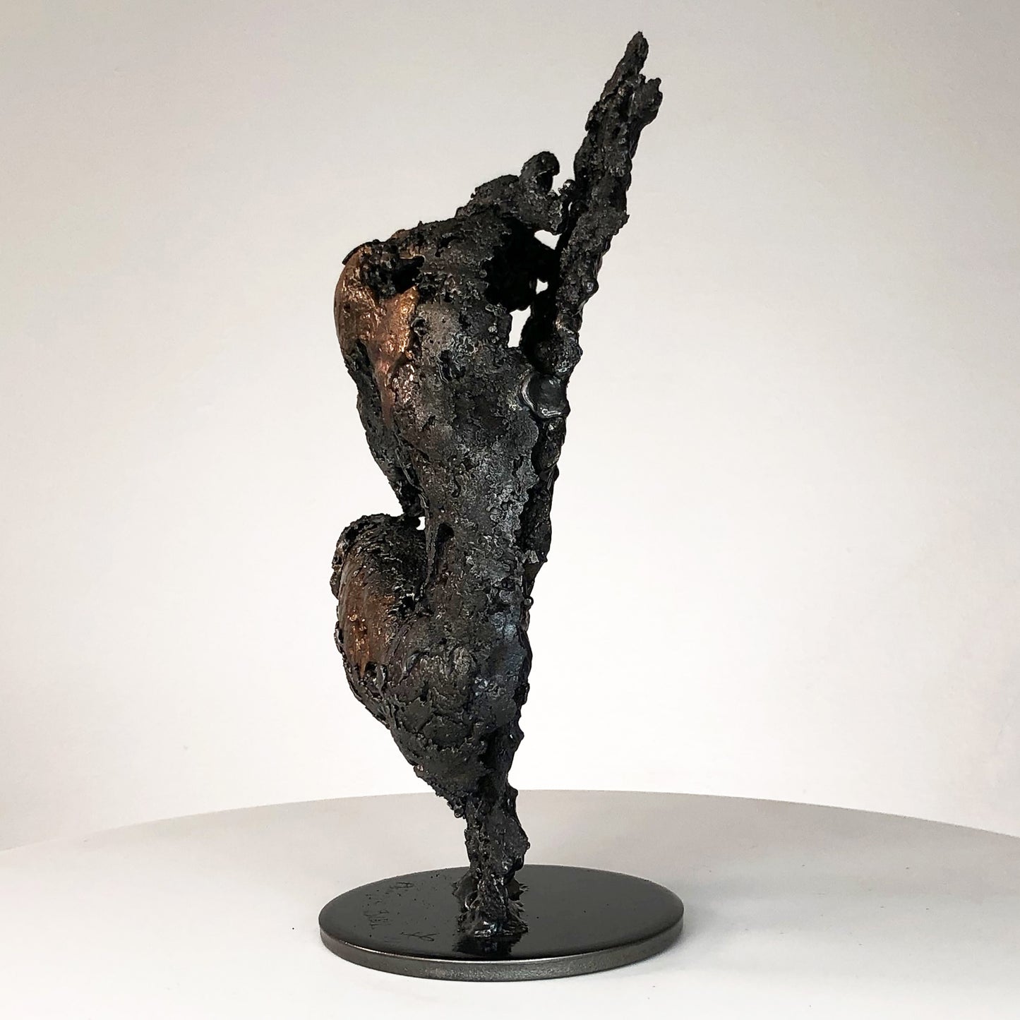 Sculpture de Philippe Buil représentant un corps d'homme accroupi intégré à une forme évoquant une montagne. Sculpture en dentelle de métal : acier et bronze.