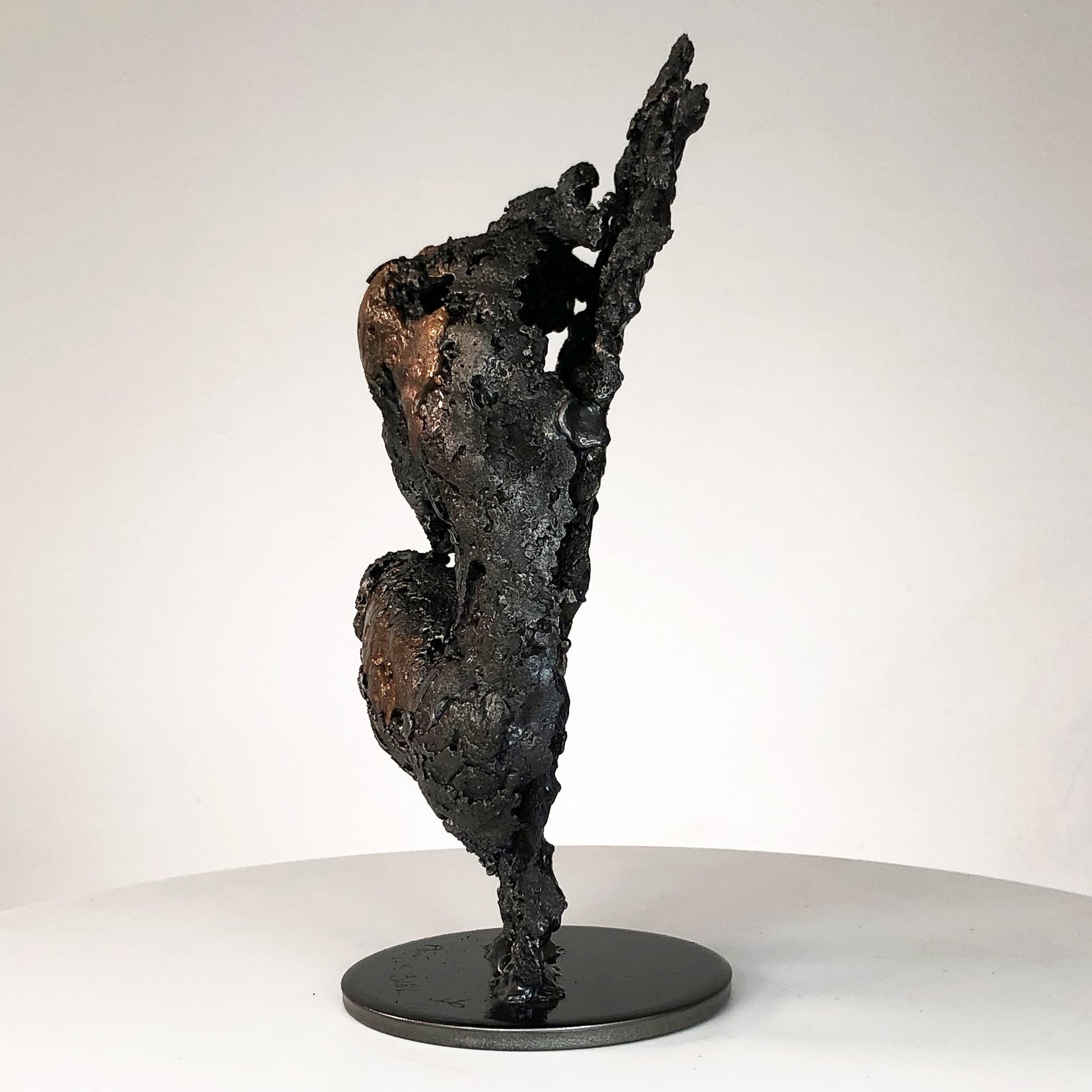 Sculpture de Philippe Buil représentant un corps d'homme accroupi intégré à une forme évoquant une montagne. Sculpture en dentelle de métal : acier et bronze.