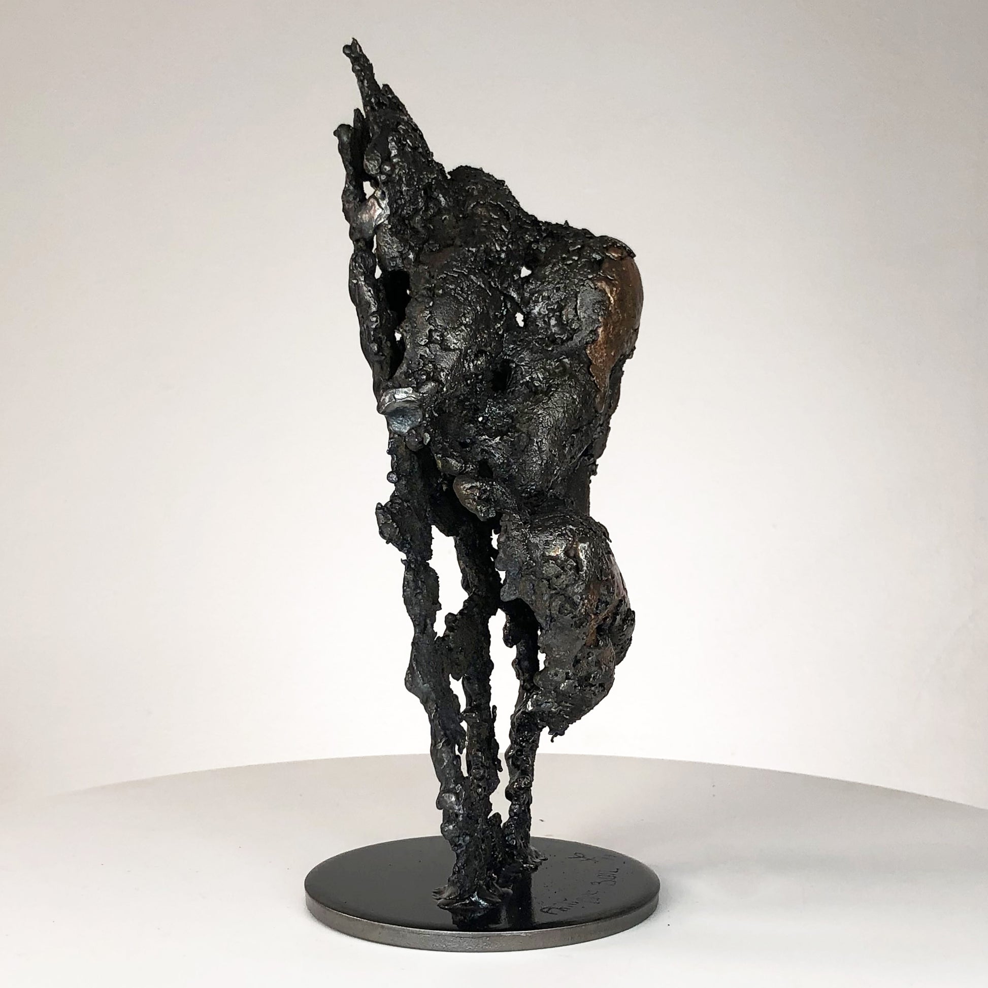 Sculpture de Philippe Buil représentant un corps d'homme accroupi intégré à une forme évoquant une montagne. Sculpture en dentelle de métal : acier et bronze.