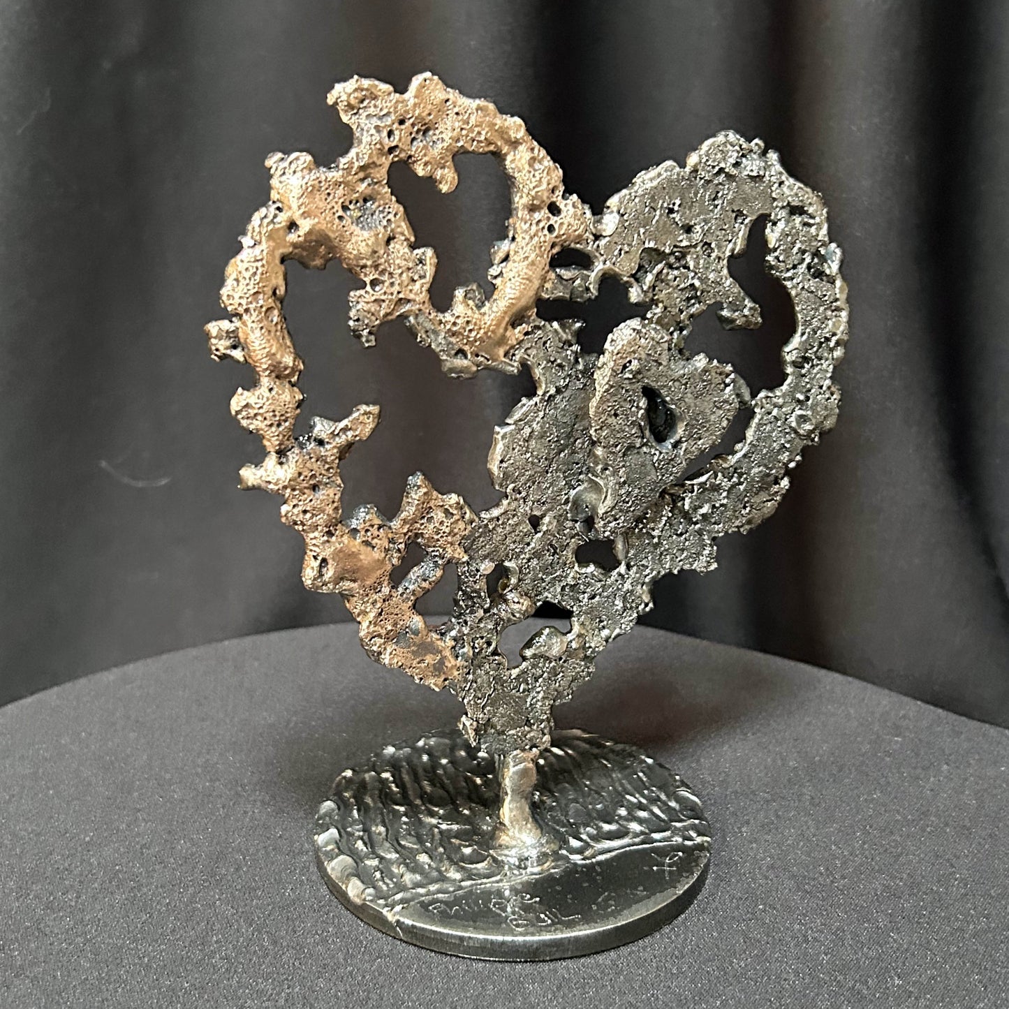 Vue de profil du coeur sculpté par Philippe Buil en acier et bronze