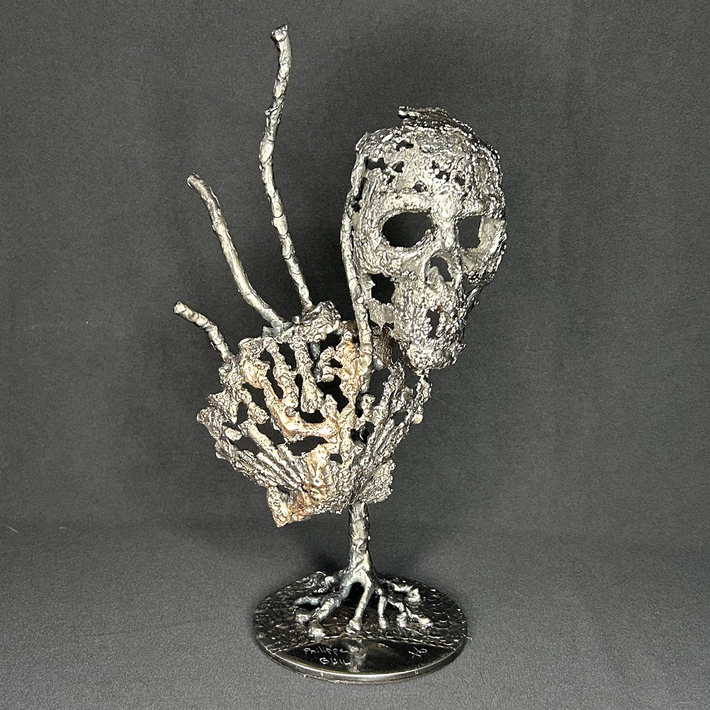 Sculpture en dentelle de métal représentant une tête de mort associée à une coquille Saint-Jacques, réalisée en acier et bronze par Philippe Buil.