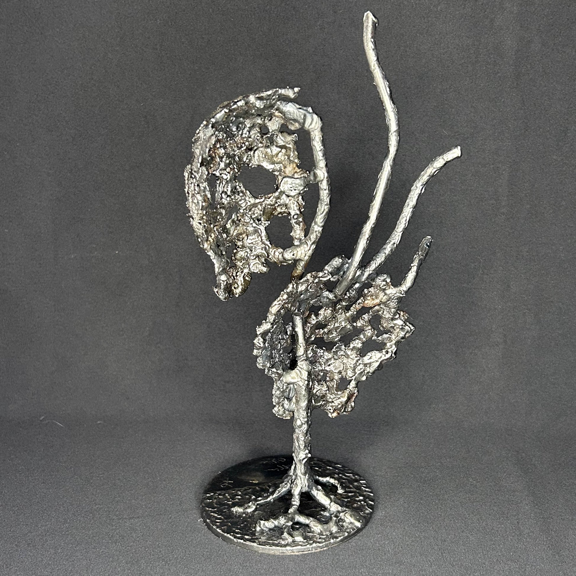 Sculpture en dentelle de métal représentant une tête de mort associée à une coquille Saint-Jacques, réalisée en acier et bronze par Philippe Buil.