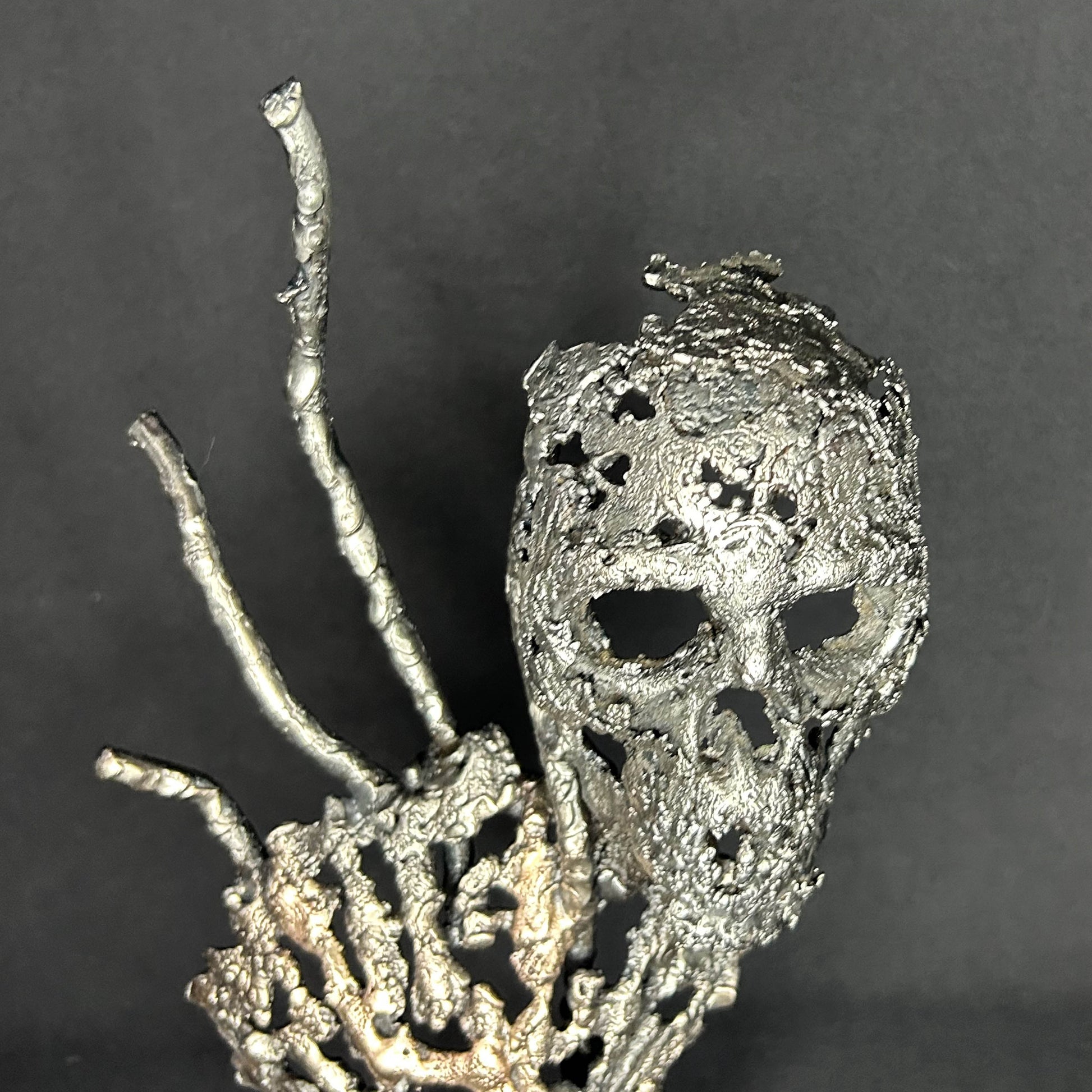 Sculpture en dentelle de métal représentant une tête de mort associée à une coquille Saint-Jacques, réalisée en acier et bronze par Philippe Buil.