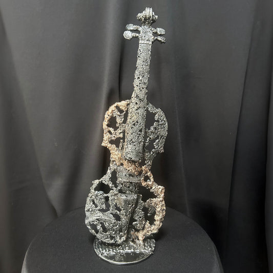 Sculpture en dentelle de métal représentant un violon ajouré, réalisée en bronze et acier par Philippe Buil — pièce unique intitulée « Le Sillage du Violon », posée sur fond sombre.