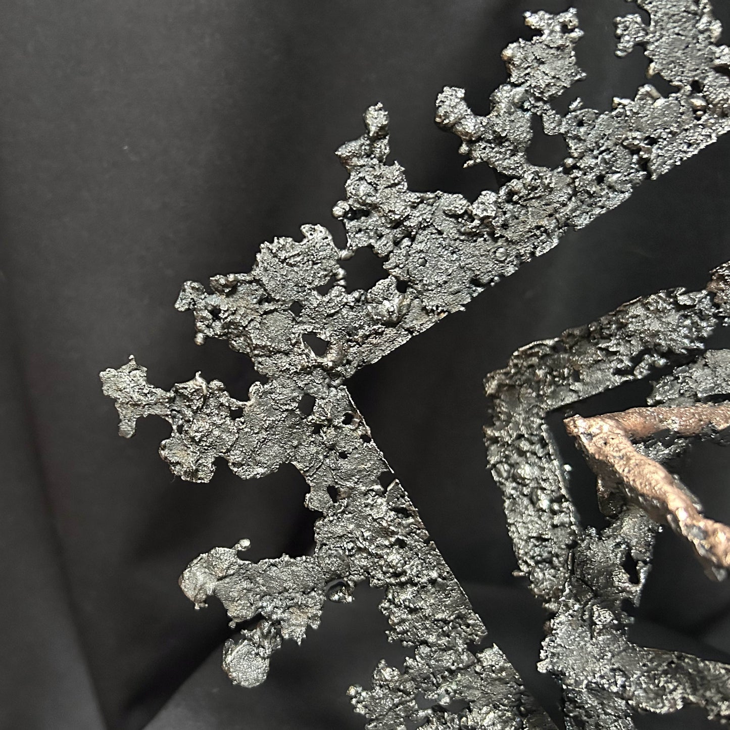 Gros plan sur la fusion du bronze et de l'acier créant une texture de dentelle métallique.