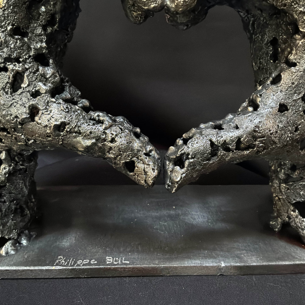 Socle métallique de la sculpture « Un échange » portant la signature de Philippe Buil