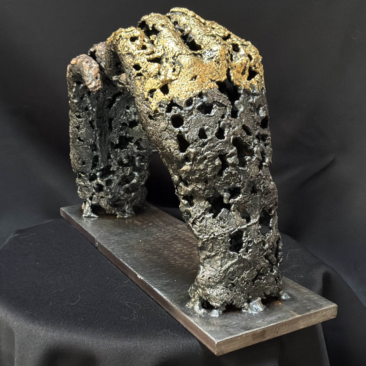 Sculpture « Un échange » vue de trois quarts, mains formant un cœur et contrastes entre métal brut et feuille d’or