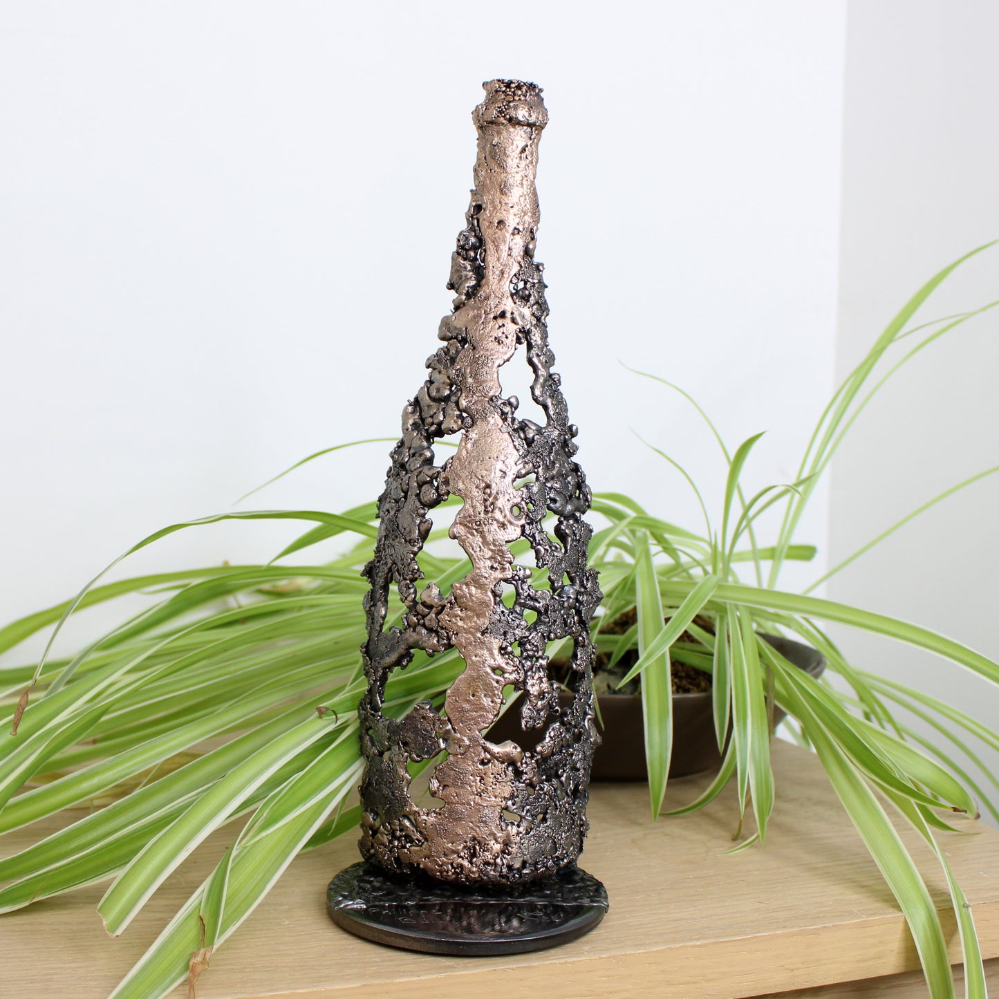 Sculpture de Philippe Buil représentant une bouteille de champagne en dentelle de métal : acier et bronze