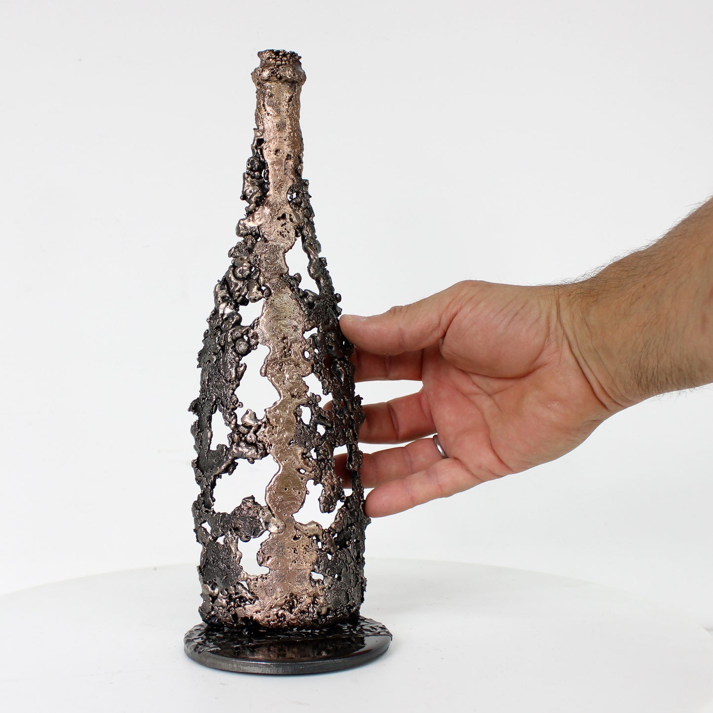 Sculpture de Philippe Buil représentant une bouteille de champagne en dentelle de métal : acier et bronze