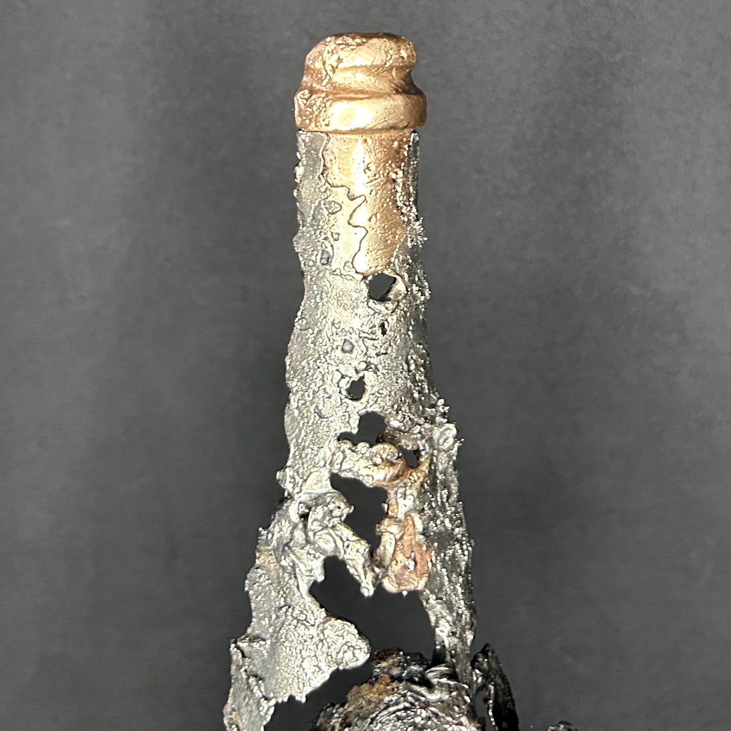 Sculpture en dentelle de métal représentant une tête de mort intégrée à une bouteille de vin, réalisée en acier et bronze par Philippe Buil.