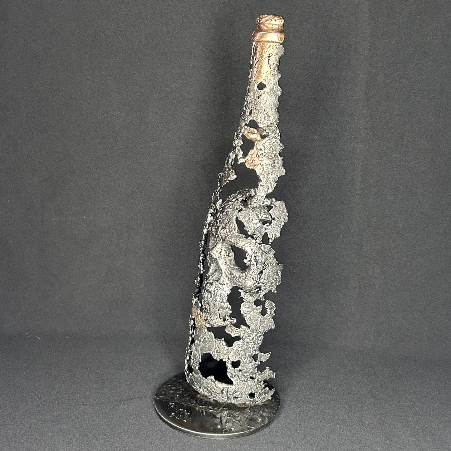 Sculpture en dentelle de métal représentant une tête de mort intégrée à une bouteille de vin, réalisée en acier et bronze par Philippe Buil.