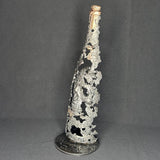 Sculpture en dentelle de métal représentant une tête de mort intégrée à une bouteille de vin, réalisée en acier et bronze par Philippe Buil.