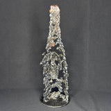 Sculpture en dentelle de métal représentant une tête de mort intégrée à une bouteille de vin, réalisée en acier et bronze par Philippe Buil.