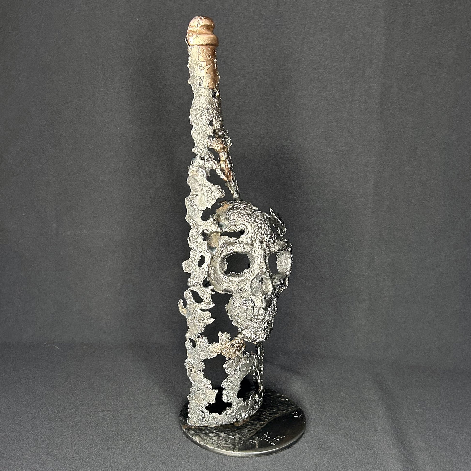Sculpture en dentelle de métal représentant une tête de mort intégrée à une bouteille de vin, réalisée en acier et bronze par Philippe Buil.