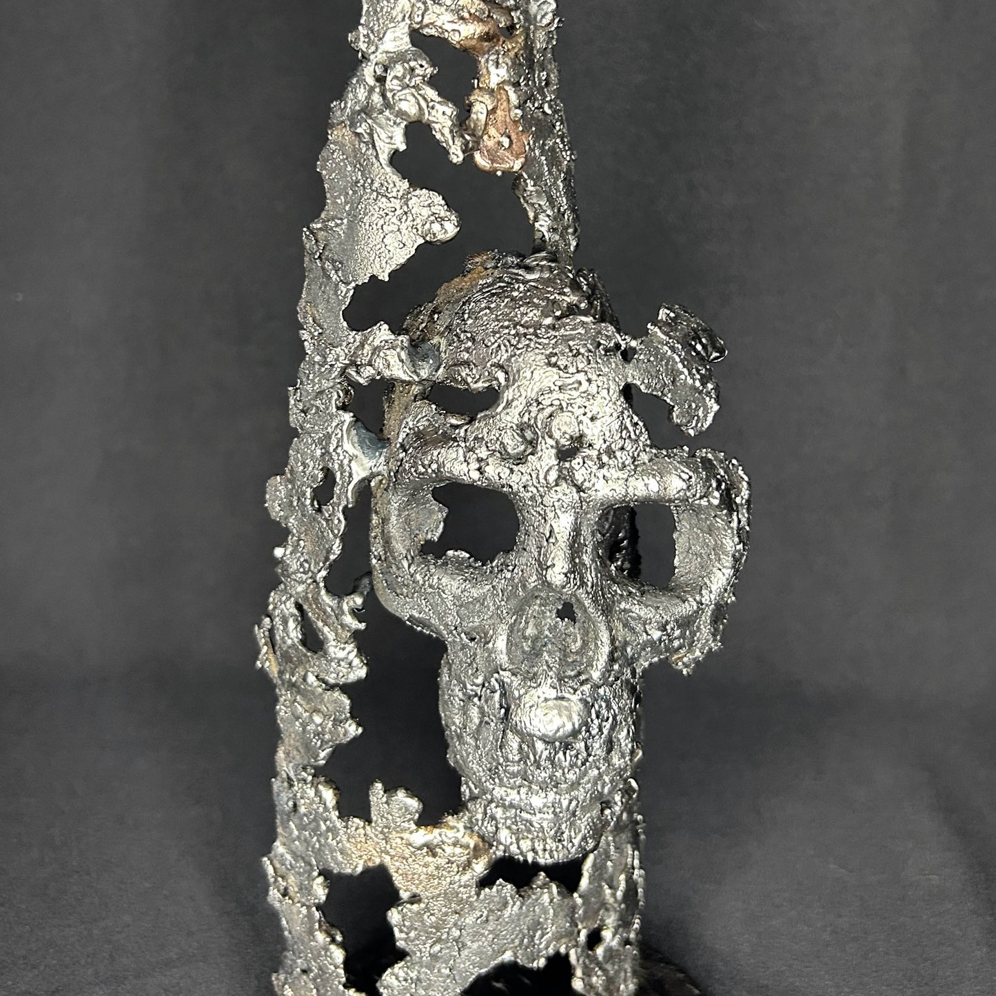Sculpture en dentelle de métal représentant une tête de mort intégrée à une bouteille de vin, réalisée en acier et bronze par Philippe Buil.