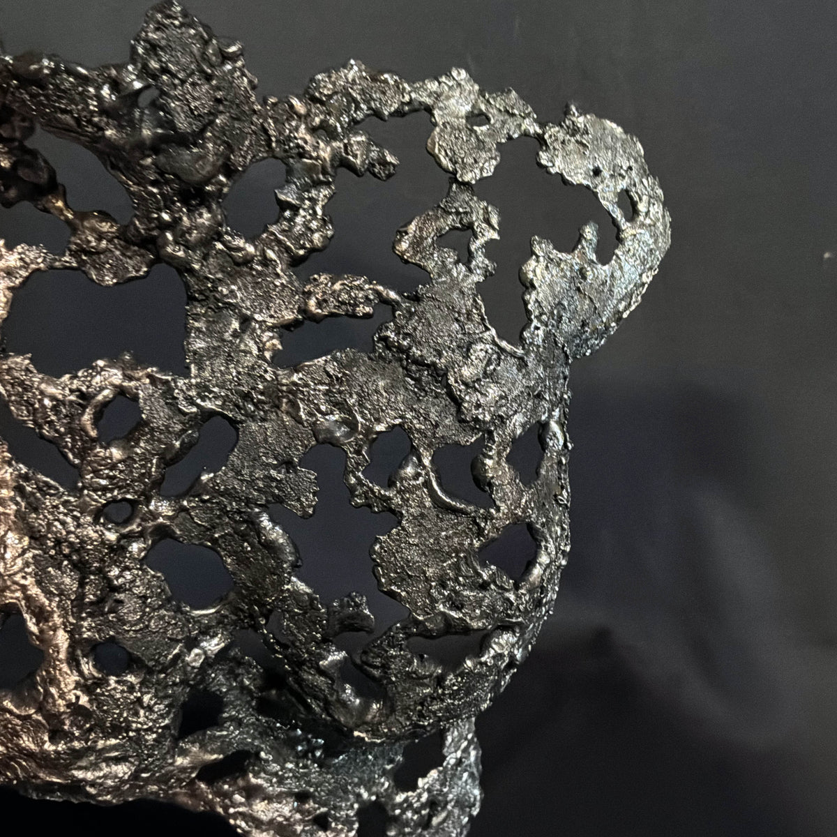 Détail rapproché de la structure ajourée de Les Traces du Temps, sculpture en métal aux lignes organiques entrelacées.