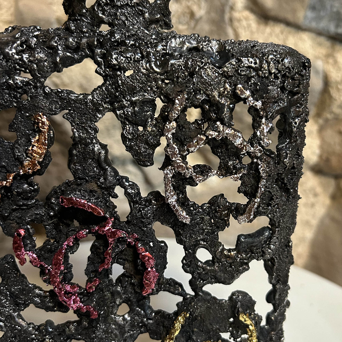 Détail d'un logo Coco Chanel aux reflets argentés et celui rosé sur la sculpture en dentelle d'acier