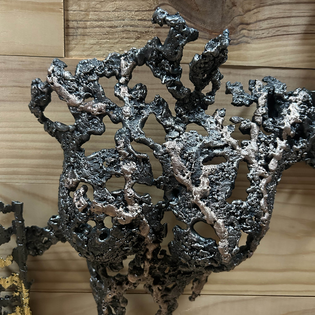 Détail de la dentelle de métal de La Splendeur du Temps sur fond de bois naturel