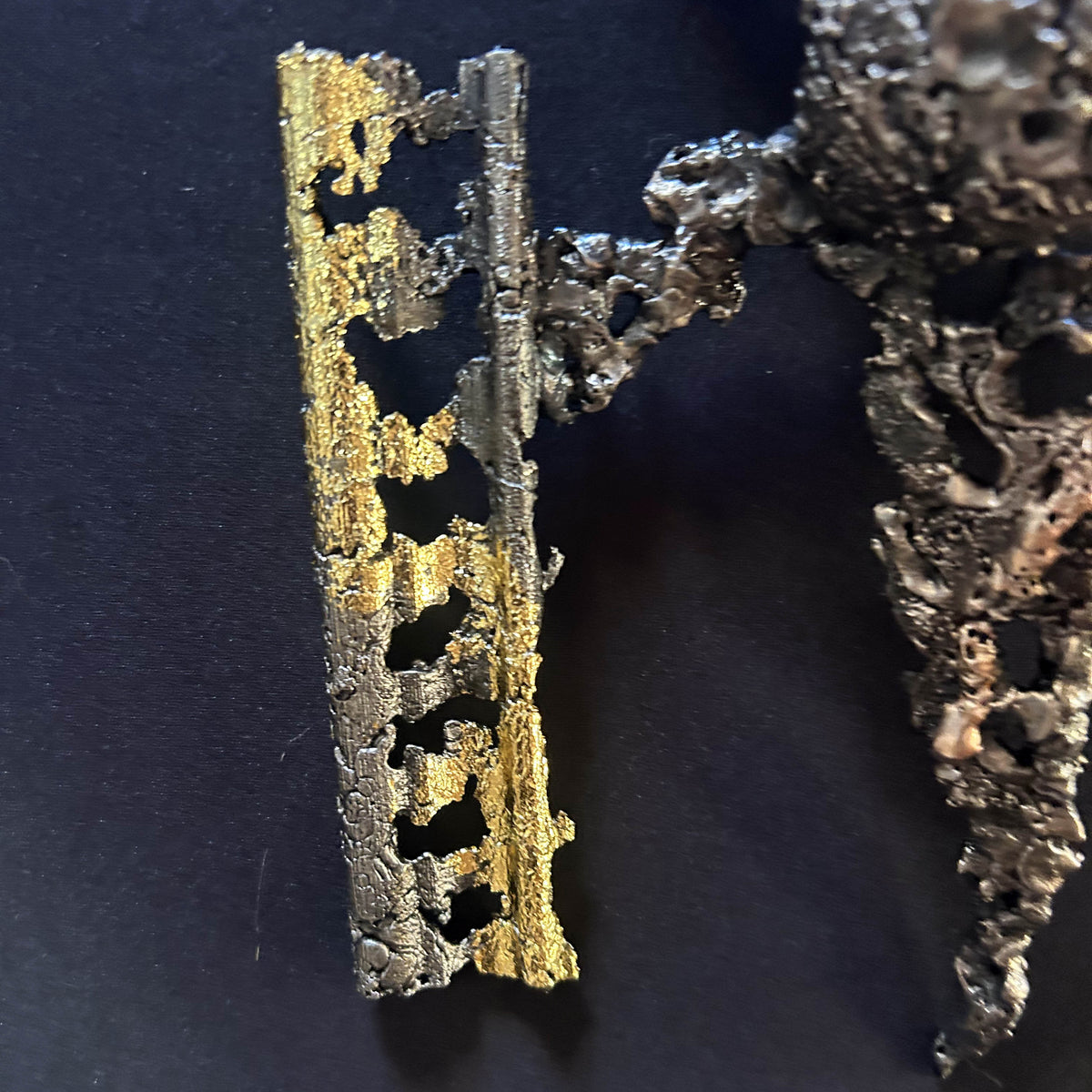 Gros plan sur la dentelle d'acier et la feuille métallisée dorée de la sculpture murale