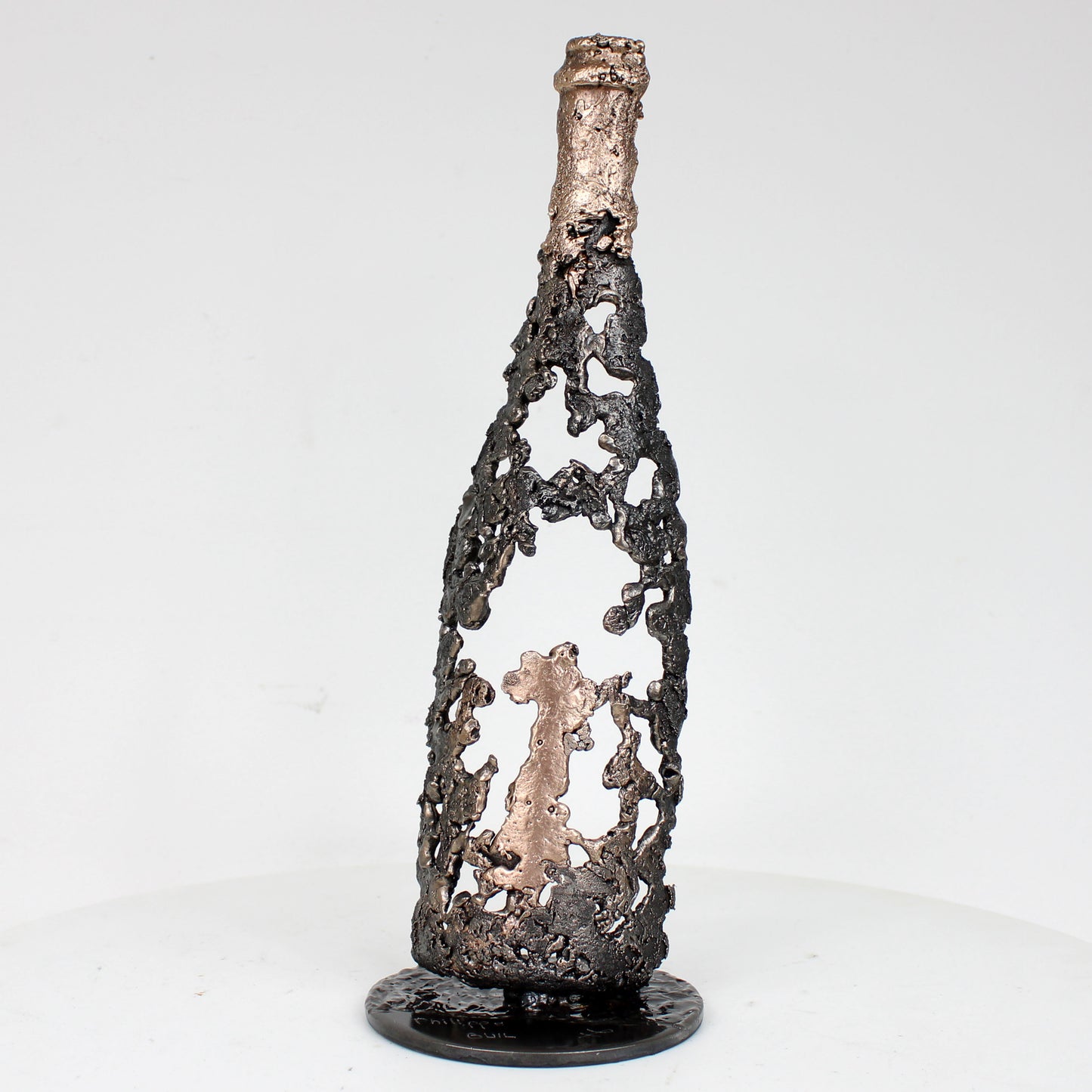 Sculpture de Philippe Buil représentant une bouteille de champagne en dentelle de métal : acier et bronze