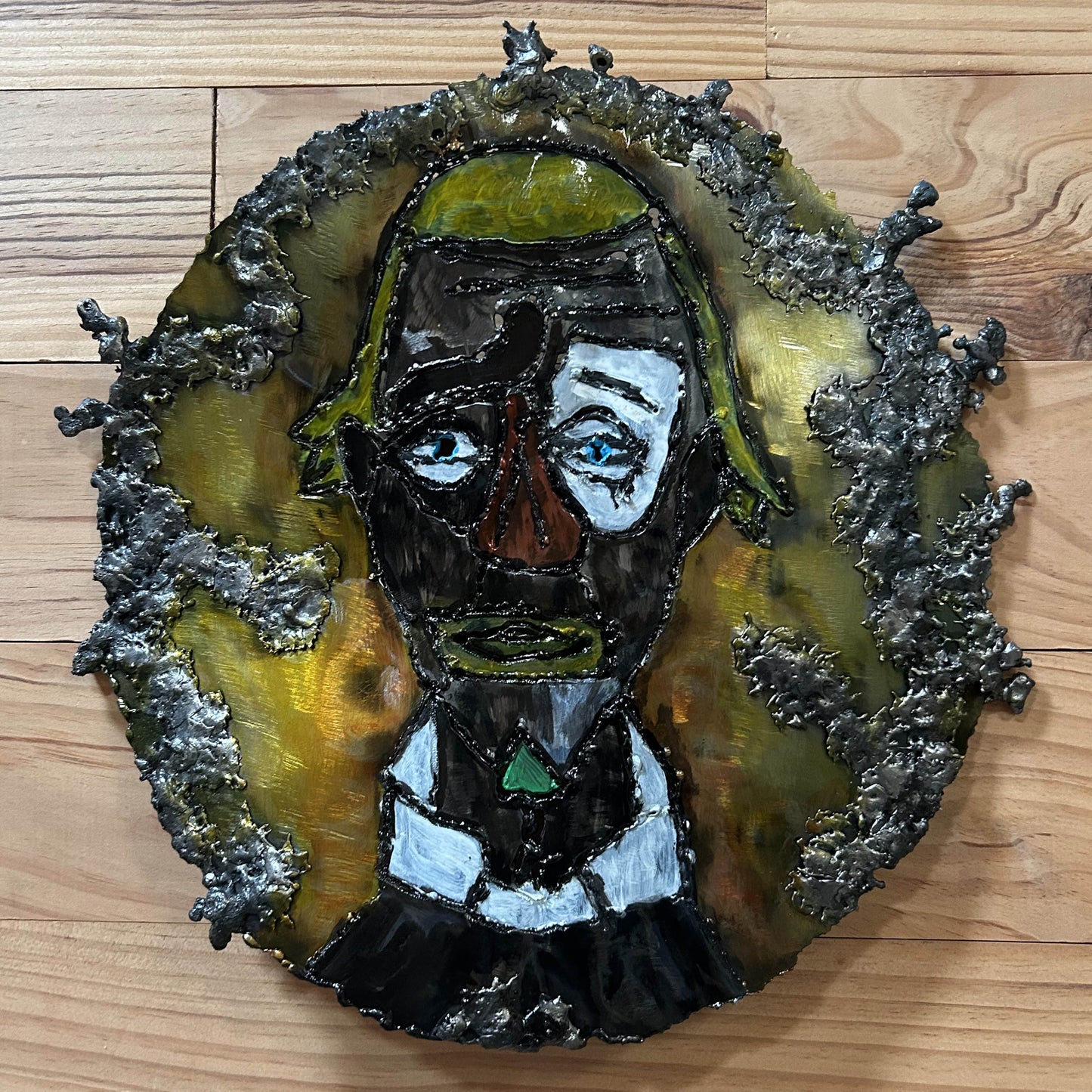 Sculpture murale en acier réalisée par Philippe Buil, représentant un visage de clown inspiré de Bernard Buffet, avec dentelle de métal et pigments colorés.