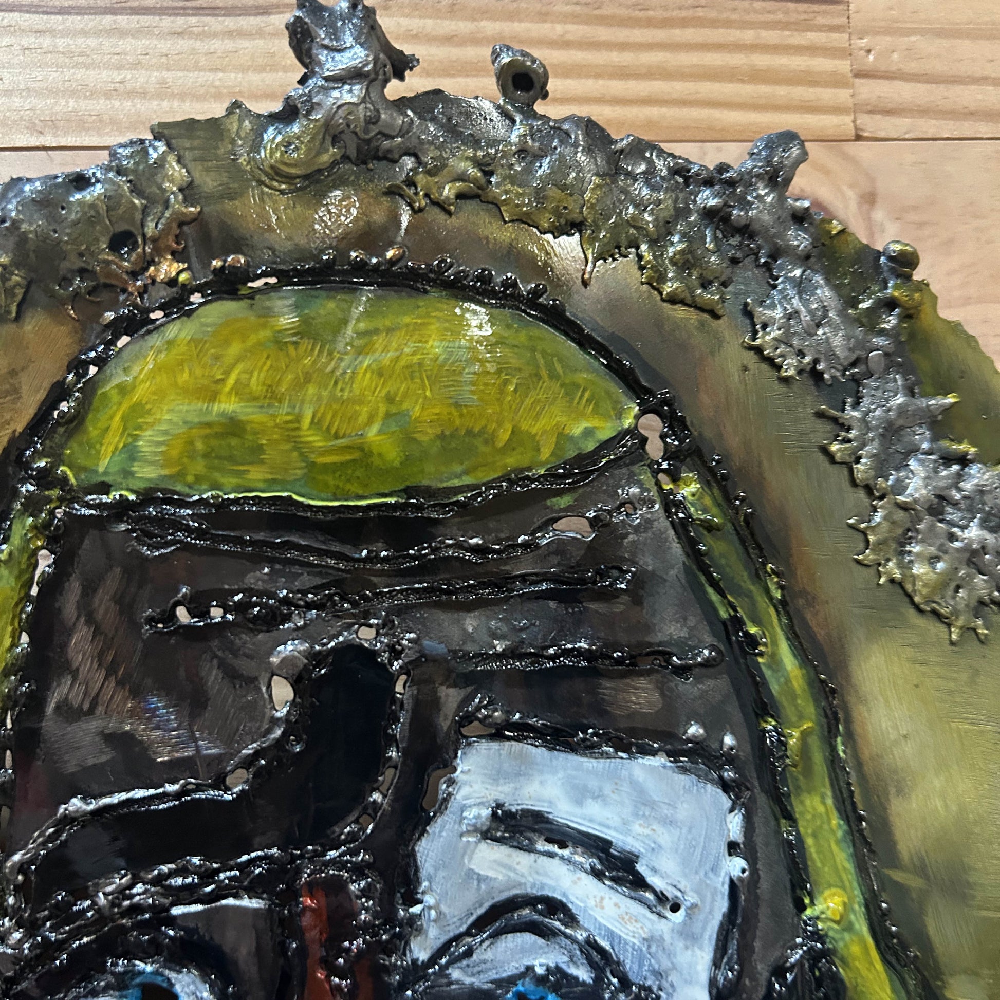 Sculpture murale en acier réalisée par Philippe Buil, représentant un visage de clown inspiré de Bernard Buffet, avec dentelle de métal et pigments colorés.