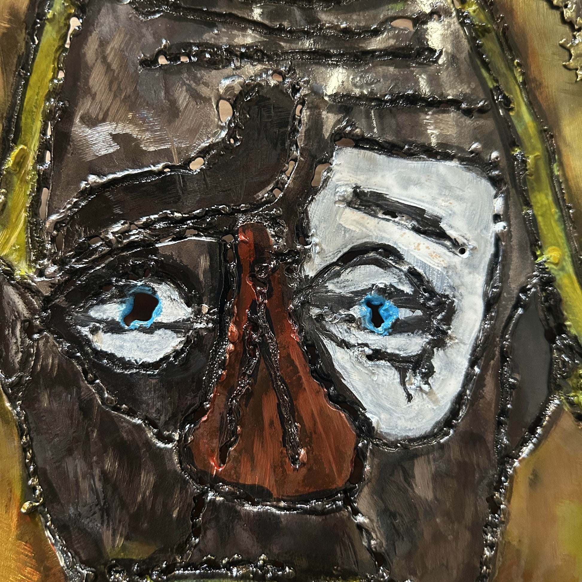 Sculpture murale en acier réalisée par Philippe Buil, représentant un visage de clown inspiré de Bernard Buffet, avec dentelle de métal et pigments colorés.
