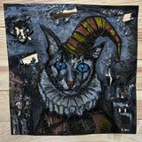Sculpture murale de Philippe Buil sur tôle d’acier découpée, dentelle de métal et pigments : un chat arlequin expressif au regard bleu hypnotique.