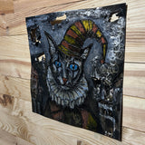 Sculpture murale de Philippe Buil sur tôle d’acier découpée, dentelle de métal et pigments : un chat arlequin expressif au regard bleu hypnotique.