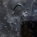 Sculpture murale carrée de 25x25 cm représentant un chat arlequin aux yeux bleus intenses, portant une collerette blanche et un chapeau rayé rouge et jaune. L’œuvre est réalisée en acier texturé et pigments, avec un fond gris brumeux et métallisé