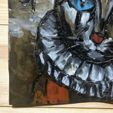 Sculpture murale carrée de 25x25 cm représentant un chat arlequin aux yeux bleus intenses, portant une collerette blanche et un chapeau rayé rouge et jaune. L’œuvre est réalisée en acier texturé et pigments, avec un fond gris brumeux et métallisé