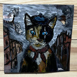 Tableau mural de 25×25 cm représentant un chat à béret dans un décor urbain gris et texturé. L’œuvre est réalisée en métal découpé avec des zones de dentelle de métal et colorée avec des pigments, créant un effet expressif et contrasté.