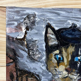 Tableau mural de 25×25 cm représentant un chat à béret dans un décor urbain gris et texturé. L’œuvre est réalisée en métal découpé avec des zones de dentelle de métal et colorée avec des pigments, créant un effet expressif et contrasté.