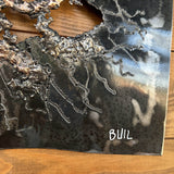 Tableau contemporain en métal de Philippe Buil représentant un visage en relief, moitié peint avec des pigments, moitié ajouré en dentelle d’acier et de bronze, créant un jeu d’ombres et de lumière.