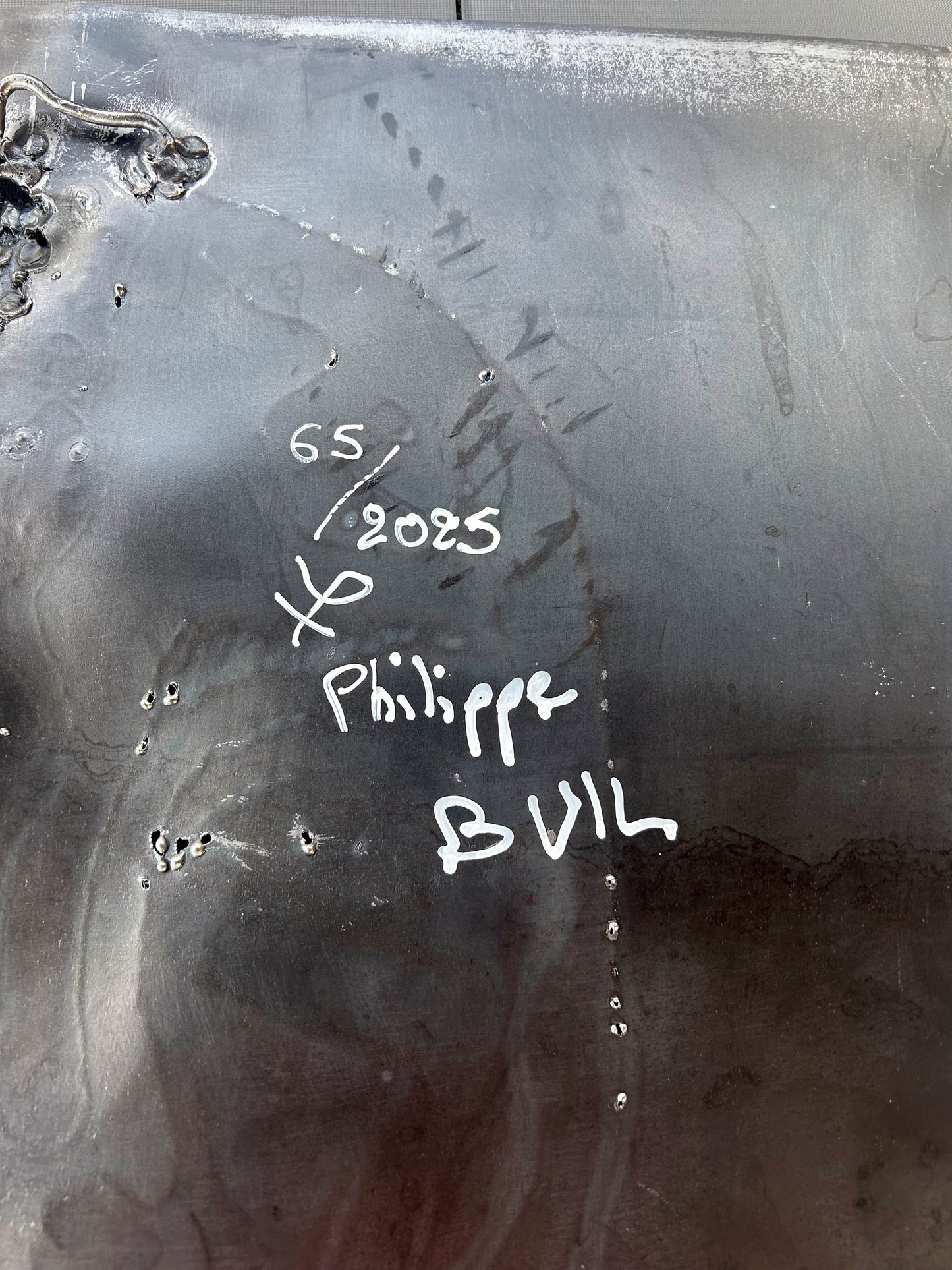 Tableau contemporain en métal de Philippe Buil représentant un visage en relief, moitié peint avec des pigments, moitié ajouré en dentelle d’acier et de bronze, créant un jeu d’ombres et de lumière.