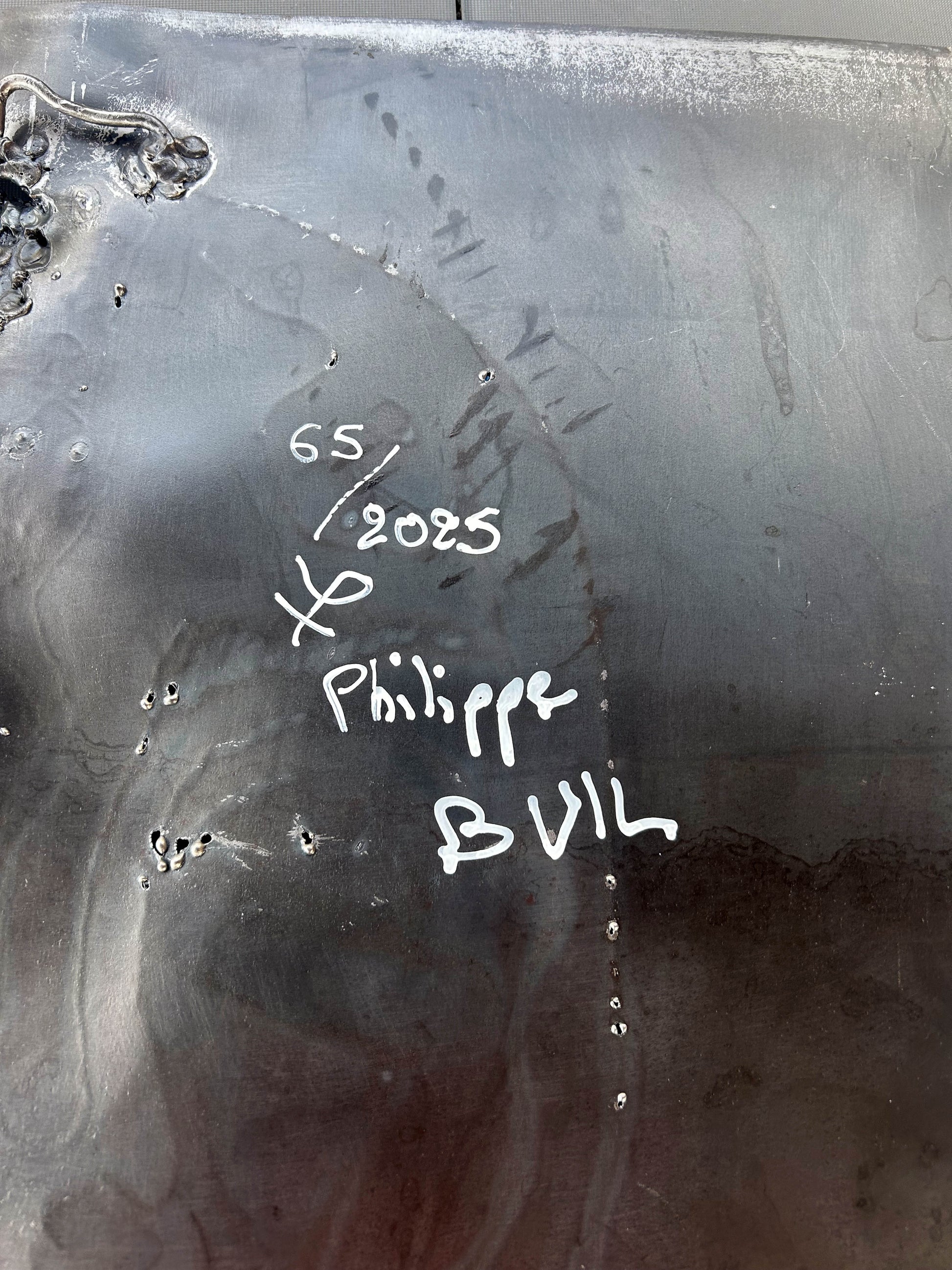 Tableau contemporain en métal de Philippe Buil représentant un visage en relief, moitié peint avec des pigments, moitié ajouré en dentelle d’acier et de bronze, créant un jeu d’ombres et de lumière.