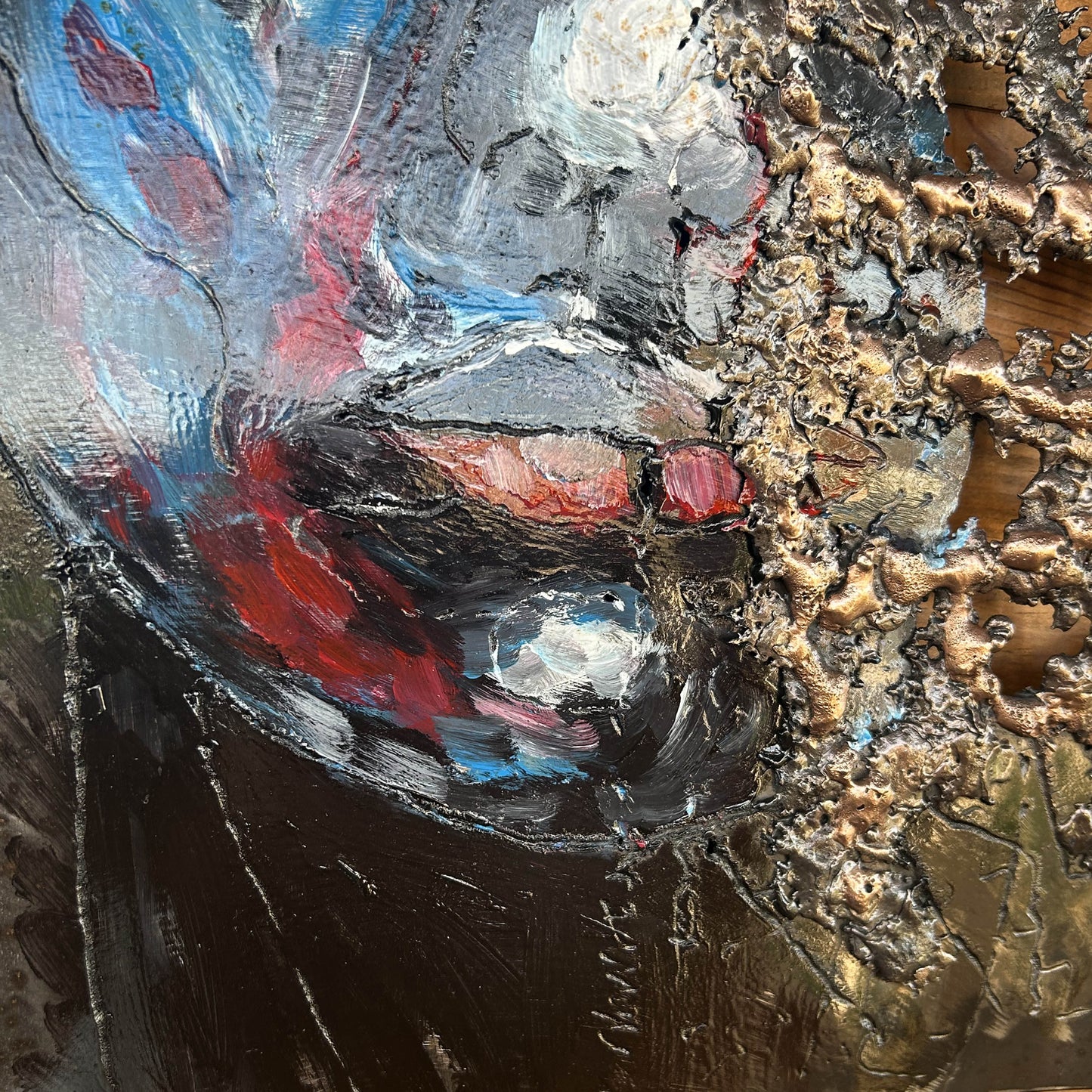 Tableau contemporain en métal de Philippe Buil représentant un visage en relief, moitié peint avec des pigments, moitié ajouré en dentelle d’acier et de bronze, créant un jeu d’ombres et de lumière.