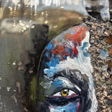 Tableau contemporain en métal de Philippe Buil représentant un visage en relief, moitié peint avec des pigments, moitié ajouré en dentelle d’acier et de bronze, créant un jeu d’ombres et de lumière.