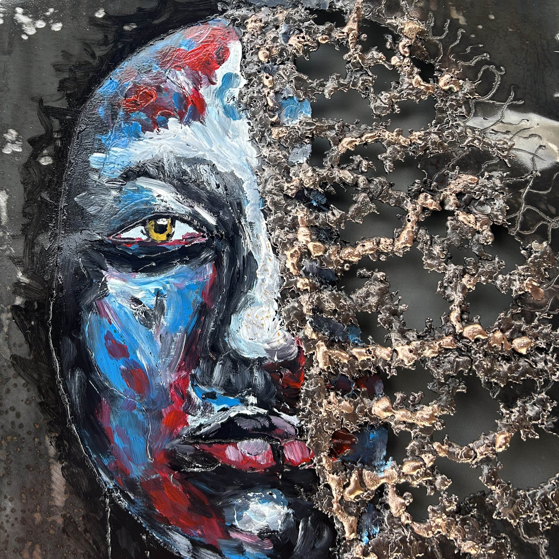 Tableau contemporain en métal de Philippe Buil représentant un visage en relief, moitié peint avec des pigments, moitié ajouré en dentelle d’acier et de bronze, créant un jeu d’ombres et de lumière.